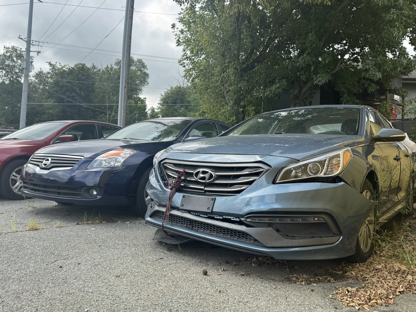 Gray sedan with visible front-end collision damage outdoors.